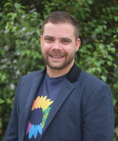 Herr Wolfram Haesler lächelt in die Kamera. Er trägt ein Jacket und ein T-Shirt